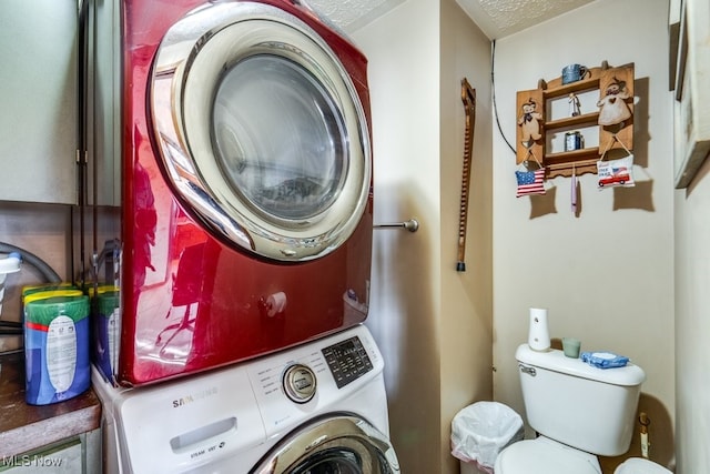 laundry area featuring stacked washing maching and dryer and a textured ceiling