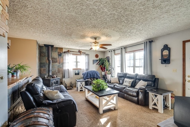 carpeted living room featuring ceiling fan, a wood stove, and a textured ceiling