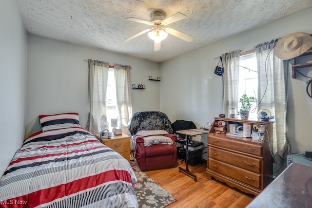 bedroom with hardwood / wood-style floors, a textured ceiling, and ceiling fan