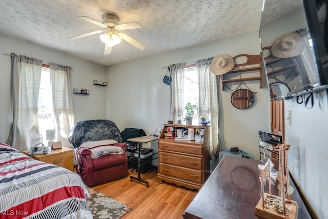 bedroom with ceiling fan, a textured ceiling, and light hardwood / wood-style flooring