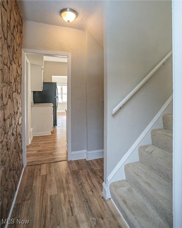 hallway with a textured ceiling and hardwood / wood-style flooring