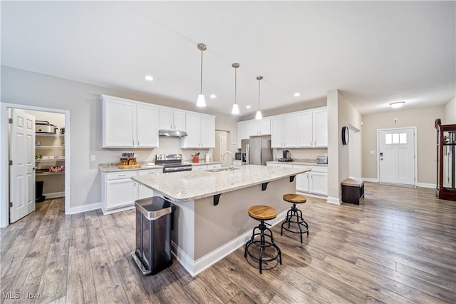 kitchen featuring appliances with stainless steel finishes, light stone counters, a kitchen island with sink, sink, and white cabinetry