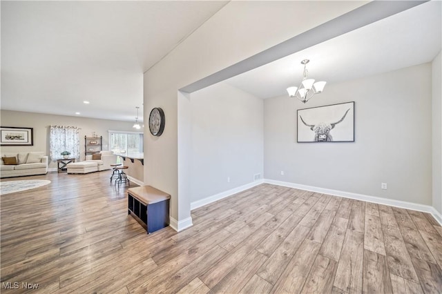 empty room with light wood-type flooring and a chandelier