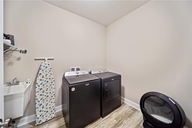 laundry room featuring light hardwood / wood-style floors, independent washer and dryer, and sink