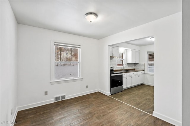 kitchen with electric range, sink, tasteful backsplash, dark hardwood / wood-style flooring, and white cabinets