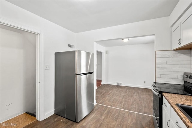 kitchen with decorative backsplash, white cabinetry, dark wood-type flooring, and appliances with stainless steel finishes