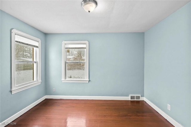 spare room with dark hardwood / wood-style floors and a healthy amount of sunlight