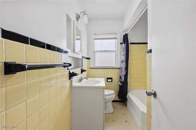 full bathroom with vanity, shower / bath combo, tile patterned floors, toilet, and tile walls