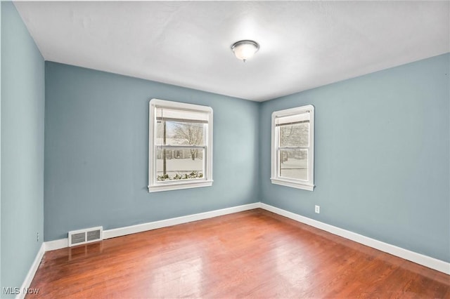 empty room with hardwood / wood-style flooring and plenty of natural light