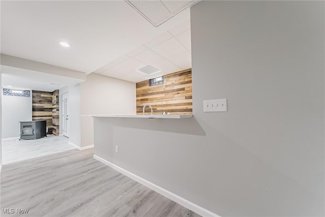 hallway featuring light wood-type flooring, sink, and wooden walls