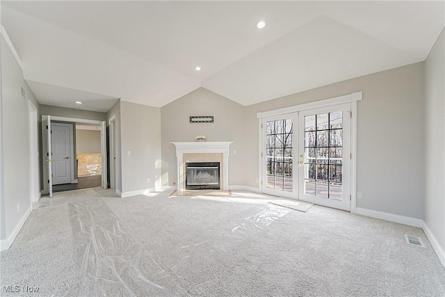 unfurnished living room featuring light carpet, french doors, and vaulted ceiling