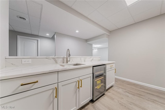 kitchen featuring a drop ceiling, white cabinets, sink, wine cooler, and light hardwood / wood-style floors