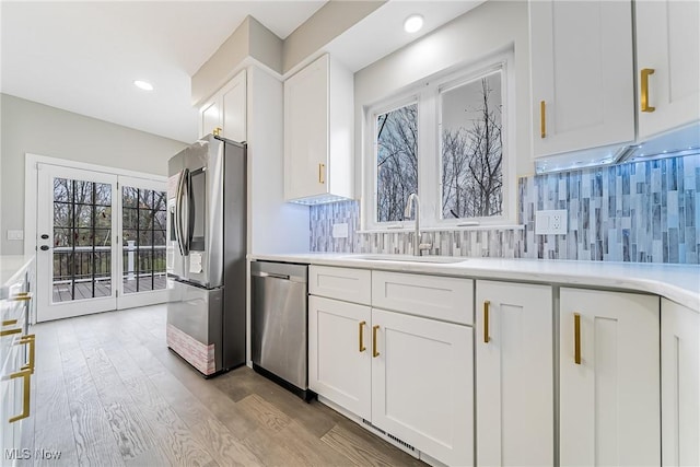 kitchen featuring decorative backsplash, plenty of natural light, white cabinets, and stainless steel appliances