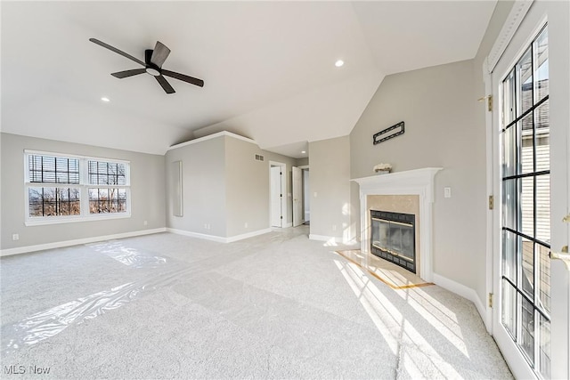 unfurnished living room with ceiling fan, a high end fireplace, light colored carpet, and vaulted ceiling