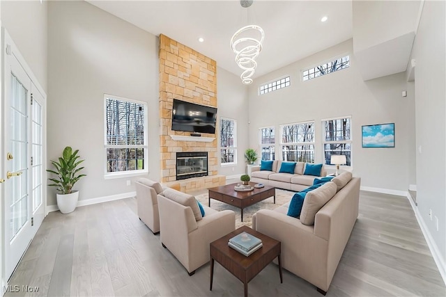 living room with a healthy amount of sunlight, a towering ceiling, a fireplace, and light hardwood / wood-style flooring