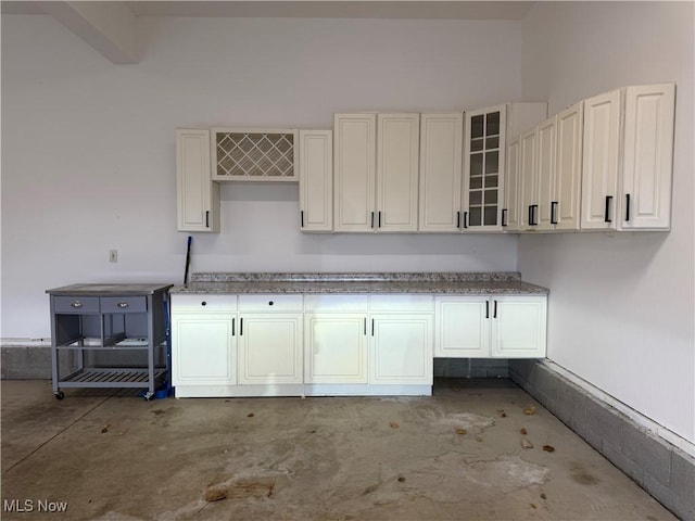 kitchen featuring white cabinets and concrete flooring