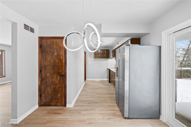 kitchen featuring light wood-type flooring, stainless steel fridge with ice dispenser, and a chandelier