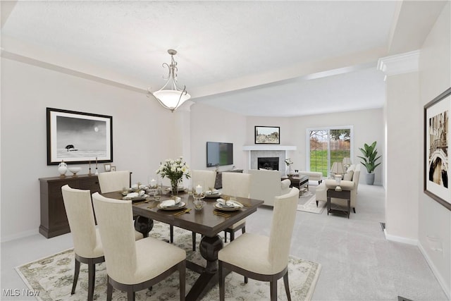 dining area featuring a tile fireplace and light carpet