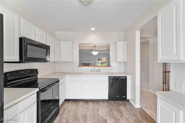 kitchen with sink, black appliances, pendant lighting, light hardwood / wood-style flooring, and white cabinetry