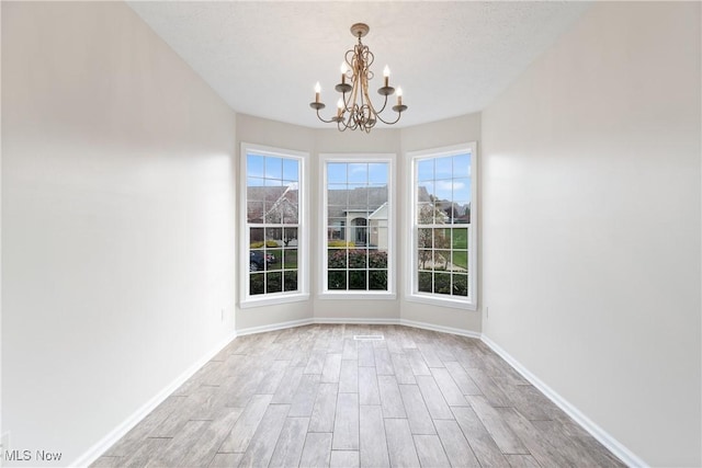 unfurnished dining area featuring a notable chandelier, light hardwood / wood-style floors, and a textured ceiling