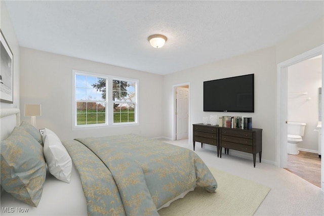 bedroom featuring ensuite bath and light colored carpet