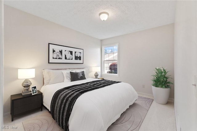 bedroom with a textured ceiling and light colored carpet