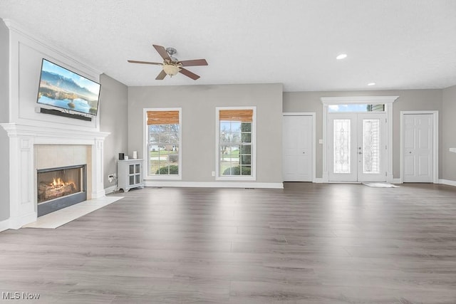 unfurnished living room with french doors, ceiling fan, hardwood / wood-style floors, and a textured ceiling