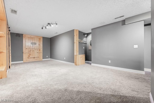 unfurnished living room featuring carpet flooring, a textured ceiling, and track lighting