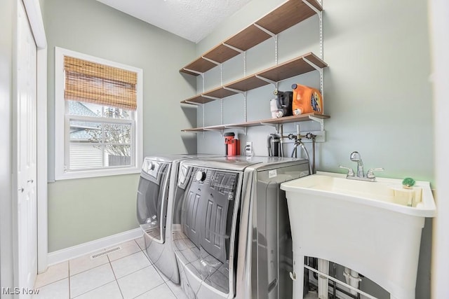 washroom featuring sink, light tile patterned floors, a textured ceiling, and independent washer and dryer