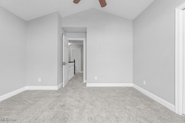 carpeted empty room with a textured ceiling, ceiling fan, and lofted ceiling