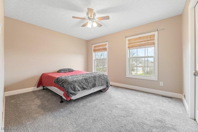 carpeted bedroom featuring a textured ceiling and ceiling fan