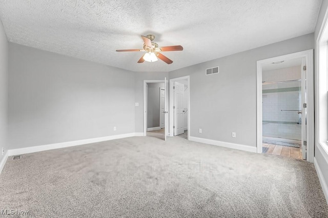 unfurnished bedroom with light carpet, a textured ceiling, connected bathroom, and ceiling fan