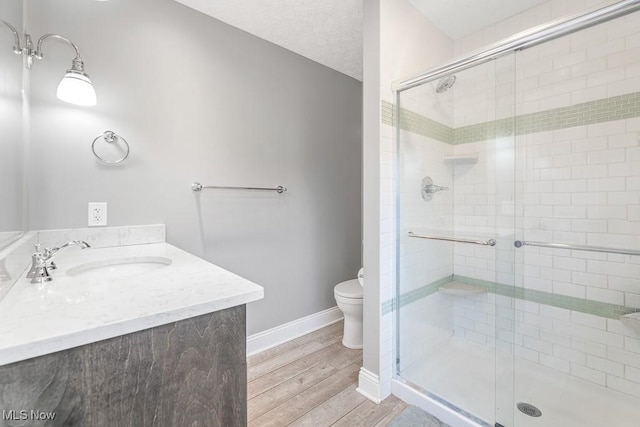 bathroom with hardwood / wood-style floors, toilet, an enclosed shower, and vanity