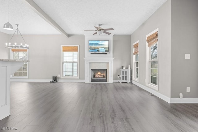 unfurnished living room featuring beam ceiling, ceiling fan, a textured ceiling, and hardwood / wood-style flooring