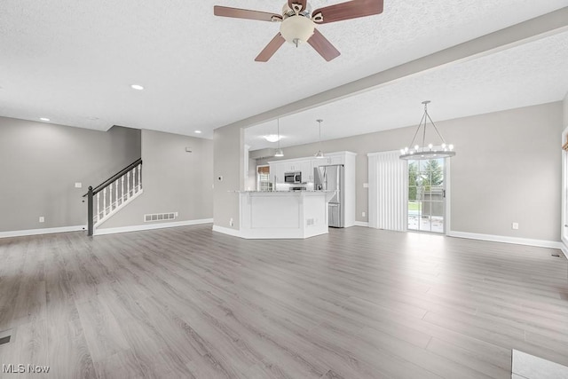 unfurnished living room with ceiling fan, light hardwood / wood-style floors, and a textured ceiling