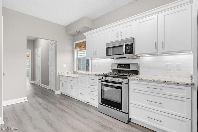 kitchen with appliances with stainless steel finishes, backsplash, and white cabinetry