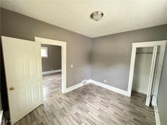 unfurnished bedroom featuring hardwood / wood-style floors, a textured ceiling, and a closet