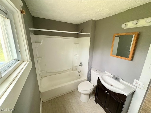full bathroom with wood-type flooring, a textured ceiling,  shower combination, toilet, and vanity