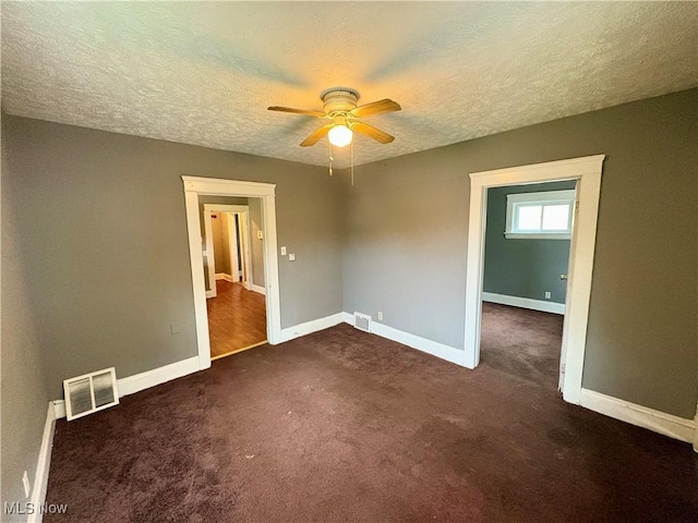 interior space with ceiling fan, dark carpet, and a textured ceiling