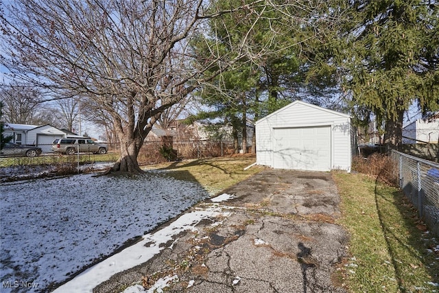 snowy yard featuring a garage and an outbuilding