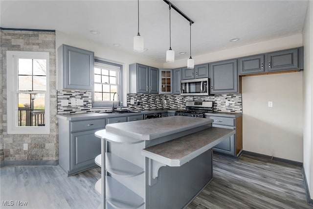 kitchen with gray cabinetry, sink, a center island, hanging light fixtures, and stainless steel appliances