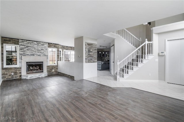 unfurnished living room featuring a tile fireplace and wood-type flooring