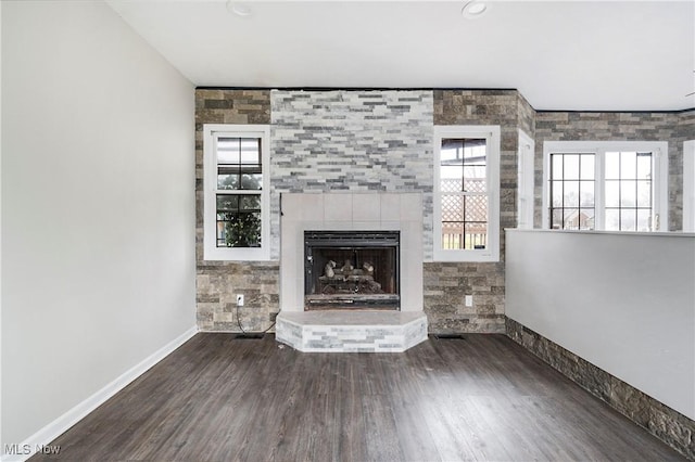 unfurnished living room featuring dark hardwood / wood-style floors and a tiled fireplace