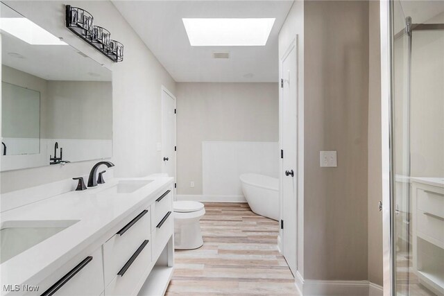 bathroom with vanity, a skylight, toilet, walk in shower, and wood-type flooring