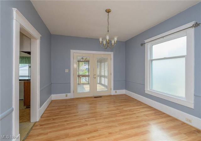 interior space featuring french doors, light wood-type flooring, and an inviting chandelier