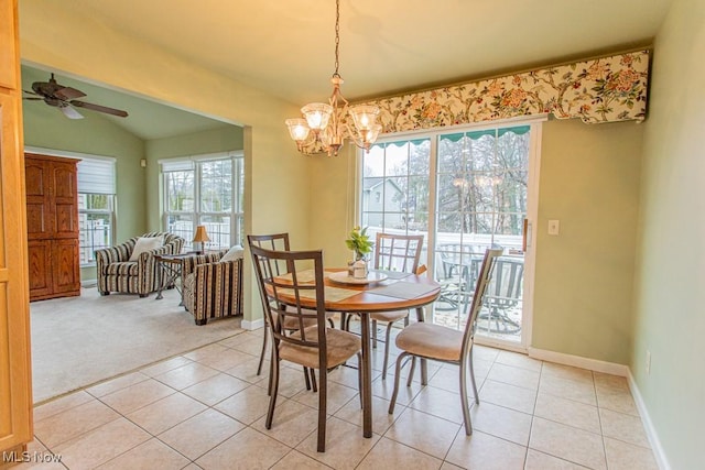 dining room featuring ceiling fan with notable chandelier, light tile patterned floors, and vaulted ceiling