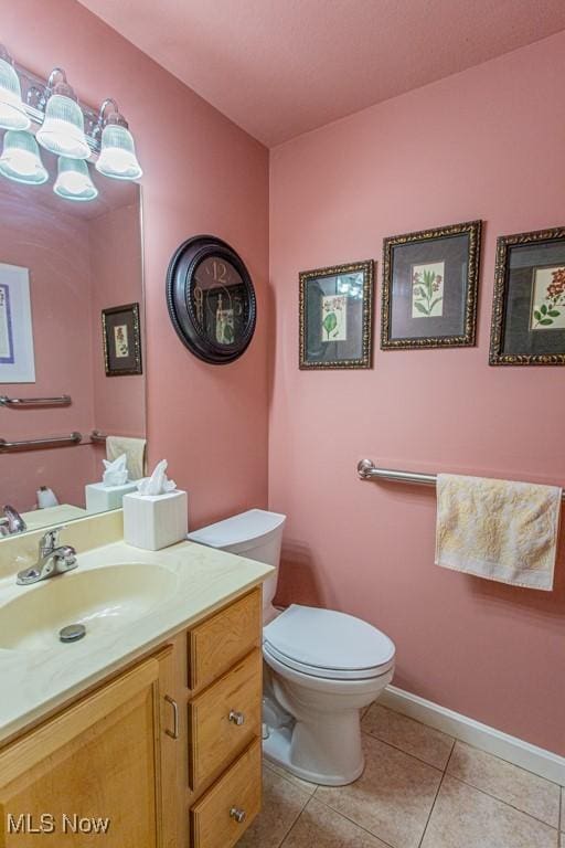 bathroom with toilet, vanity, and tile patterned floors