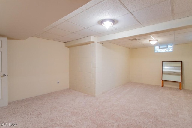 basement with a paneled ceiling and light colored carpet