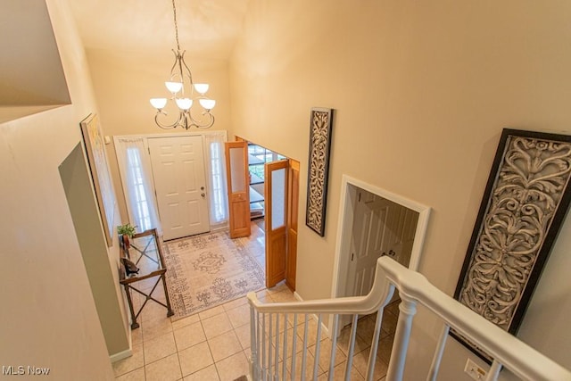 foyer with light tile patterned floors, a high ceiling, and a chandelier