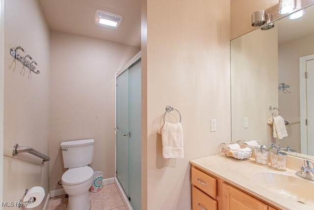 bathroom featuring tile patterned floors, vanity, an enclosed shower, and toilet